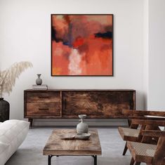 a living room filled with furniture and a painting hanging on the wall above it's coffee table