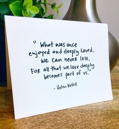 a card with a quote on it sitting next to a potted plant and vase