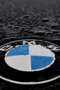 the bmw logo is shown on a wet surface with drops of water around it and black background