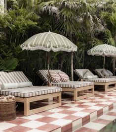 lounge chairs and umbrellas are lined up by the pool