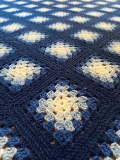 a crocheted blanket with blue, yellow and white flowers on it's edges