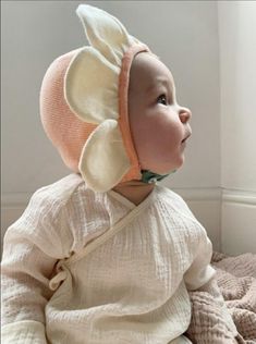 a baby wearing a bonnet sitting on top of a bed