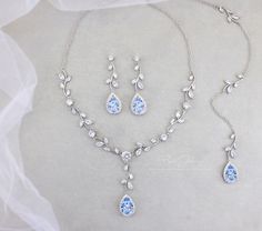 a necklace and earring set with blue crystal stones on a white cloth covered surface