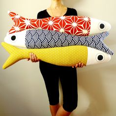 a woman is holding four decorative pillows in her hands