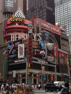 a busy city street filled with lots of tall buildings and people walking across the street