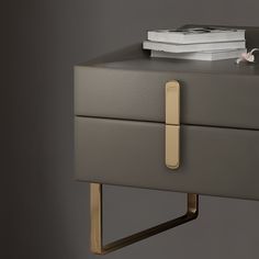 a grey and gold nightstand with books on top