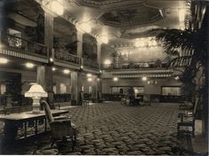 an old black and white photo of a large room with tables, chairs, and chandeliers