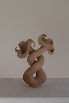 a sculpture is sitting on a table with a white cloth around it and the base has a snake like design