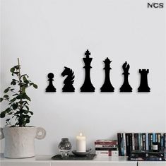 a white table topped with a vase filled with flowers next to a wall mounted chess set