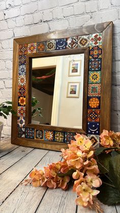 a mirror sitting on top of a wooden table next to a potted plant and flowers