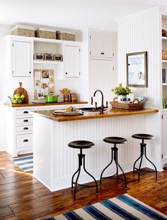 a kitchen with three stools in front of an island and white cabinets on the wall