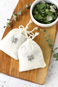 two bags with plants in them sitting on a cutting board next to a small bowl