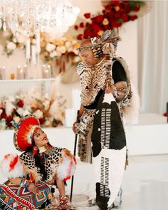 two people dressed in costumes standing next to each other on the floor with christmas decorations behind them