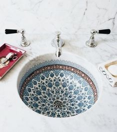 a blue and white sink sitting on top of a counter next to a faucet