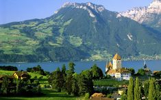 a scenic view of a church in the middle of a lake with mountains in the background