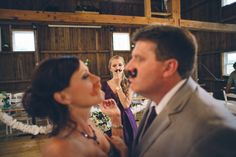 a man and woman standing in front of each other at a wedding reception with the bride looking on