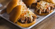 three pulled pork sandwiches with coleslaw slaw on a metal tray, ready to be eaten