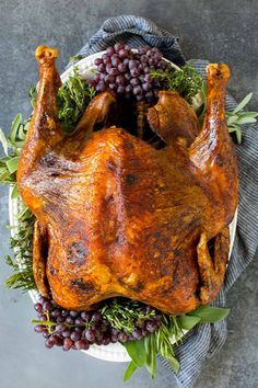 a roasted turkey on a platter with grapes and herbs