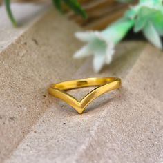 a gold ring sitting on top of a stone slab next to a green leafy plant