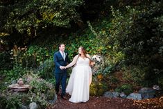 a bride and groom holding hands in the garden