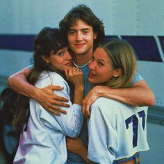 three young people hugging each other in front of a van with their arms around one another