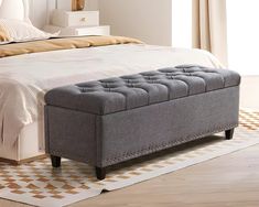 a bed with a gray tufted bench on top of it