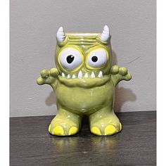 a green ceramic monster sitting on top of a wooden table