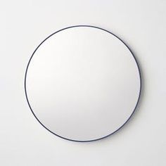 a round mirror sitting on top of a white wall next to a black and blue object