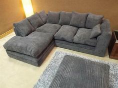 a large gray sectional couch sitting on top of a white floor next to a rug