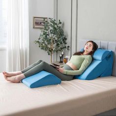 a woman laying on top of a bed next to a potted plant in a living room