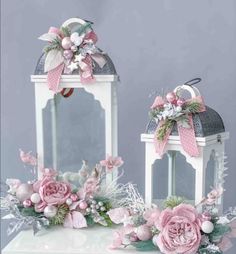 two white lanterns decorated with pink flowers and bows