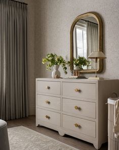 a white dresser sitting in front of a window with a mirror on top of it