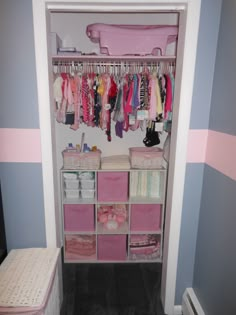 an organized closet with pink and white bins for baby's clothes, toys and other items