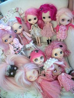 a group of dolls sitting on top of a white couch next to each other with pink hair