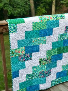 a blue and green quilt on a wooden deck