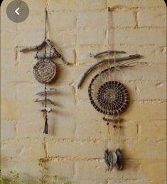 two wall hangings made out of driftwood are on the side of a brick wall