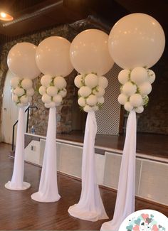 white balloons are arranged in the shape of flowers and greenery on top of pedestals