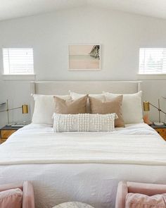 a bed with white sheets and pillows in a bedroom next to two nightstands on either side of the bed