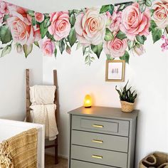 a bedroom with flowers painted on the wall and a dresser in front of it, next to a bed