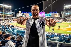 a baseball player standing in the middle of a stadium holding his hands up and smiling