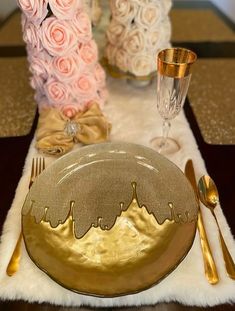 the table is set with pink roses and goldware