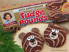 two cookies with chocolate icing and faces on them next to a box of fudge rounds