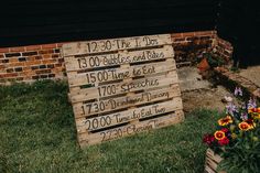 a wooden sign sitting in the grass next to flowers