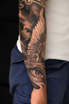 a man's arm with an owl and eye tattoo on the left sleeve, which has clouds in the background