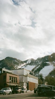 cars are parked in front of a building with a mountain in the background