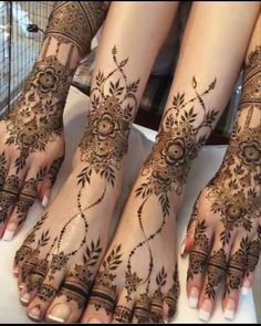 three feet with henna tattoos on them and one foot in the shape of a flower