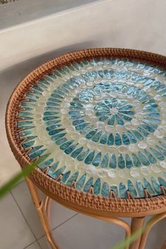 a wicker table topped with a blue and white glass mosaic design on top of it