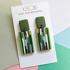 a pair of green and pink earrings sitting on top of a piece of paper