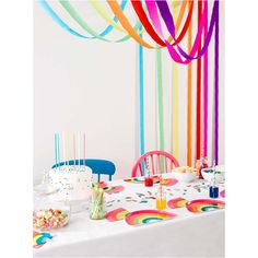 a table topped with lots of colorful streamers and cake next to a white wall