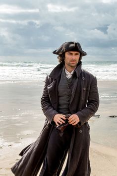 a man in a pirate costume standing on the beach with his hands in his pockets